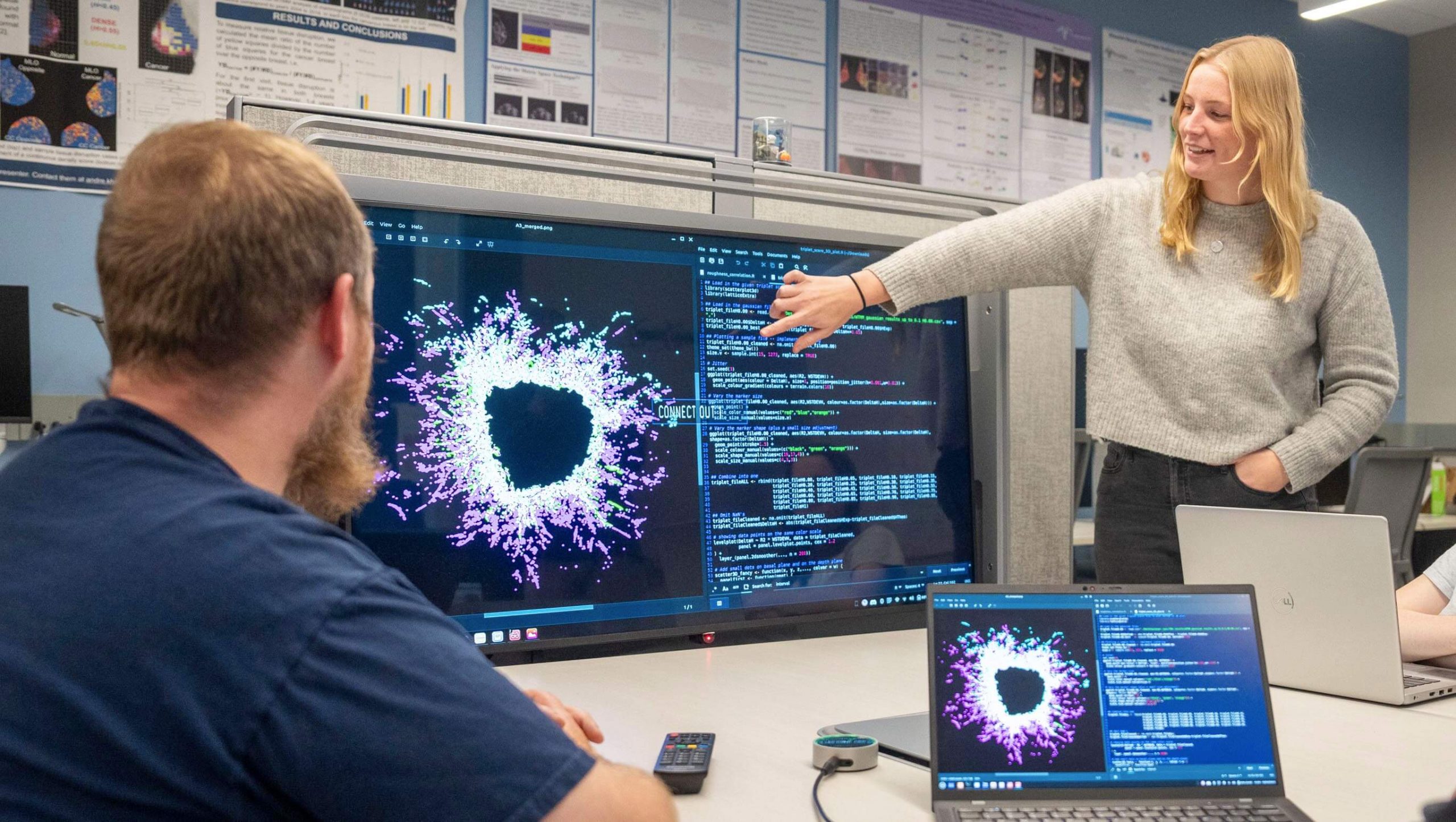 A photo of two students looking at a screen