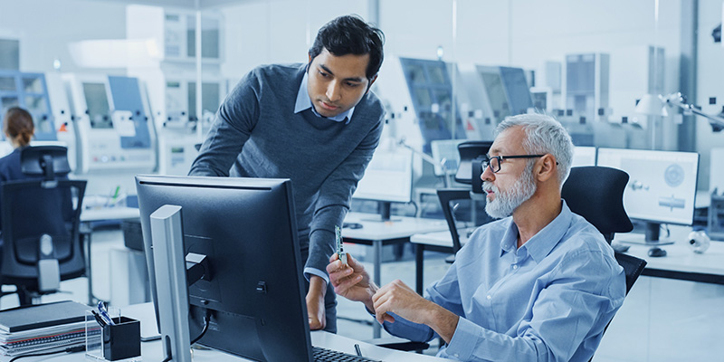 Two men looking at a computer and talking to each other