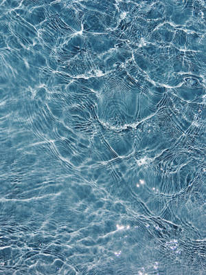 Close-up of sunlit water ripples with shimmering light patterns. — iPhone 8 Wallpaper