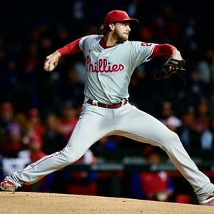 Honkbalwerper in Phillies-uniform gooit pitch tijdens nachtwedstrijd. — Dynamisch Achtergronden