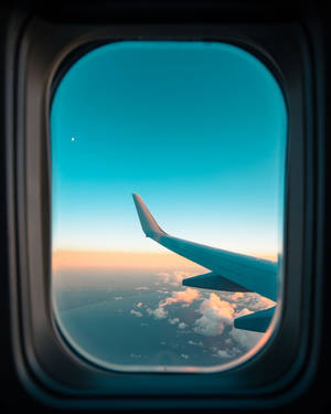 Airplane wing seen through window during sunset with colorful clouds. — Travel Wallpaper