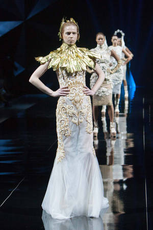Modelo em vestido haute couture dourado e branco andando na passarela. — Moda Papéis de Parede
