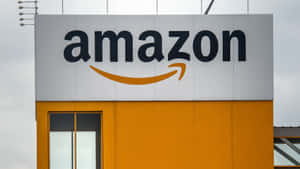 Logo Amazon sur un bâtiment jaune et blanc sous ciel nuageux — Amazon Fonds d'écran