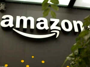 Enseigne du logo Amazon avec feuillage vert et lumières jaunes en arrière-plan. — Amazon Fonds d'écran