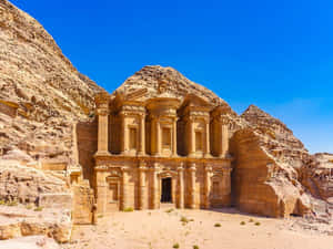 Antigo templo de pedra esculpido em desfiladeiro do deserto sob céu azul claro — Edifício Papéis de Parede