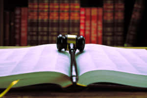 Marteau de juge sur livre juridique ouvert avec livres de droit derrière — Applicable Fonds d'écran