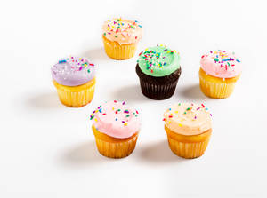 Seis cupcakes variados con chispas de colores sobre una superficie blanca. — Cupcake Fondos de pantalla