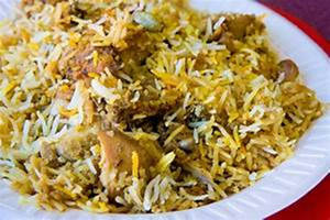 Gylden biryani-ris med kyllingestykker i en hvid papirtallerken. — Mad Wallpapers