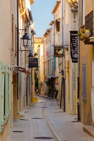 Narrow sunlit street with pastel buildings and hanging lanterns. — Authentic Wallpaper