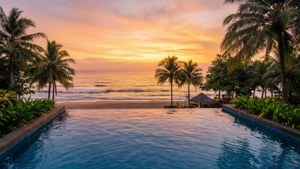 Infinity pool overlooking ocean at sunset with palm trees and lush greenery. — Hotel Wallpaper