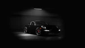 Auto sportiva nera Porsche 911 illuminata da luce a soffitto in garage scuro. — Auto Sfondi