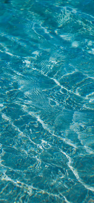Close-up of turquoise pool water with rippling sunlight reflections. — iPhone Xr Wallpaper