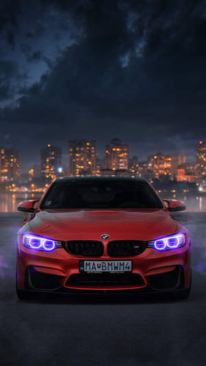 BMW sportiva rossa con fari blu parcheggiata di notte in una città con edifici illuminati. — Auto Sfondi