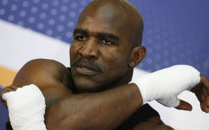 Um boxeador musculoso com ataduras brancas nas mãos descansa os braços cruzados. — Boxe Papéis de Parede