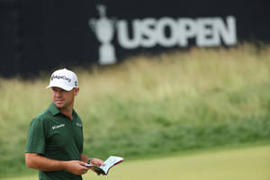 Professionel golfspiller gennemgår scorekort under US Open-turnering på grøn bane. — Golfbane Wallpapers