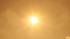 Un sole splendente che brilla attraverso nuvole dorate e nebbiose con raggi stellari. — Calore Sfondi