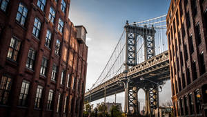 Ponte de Manhattan emoldurada por edifícios históricos de tijolo ao pôr do sol. — Edifícios Papéis de Parede