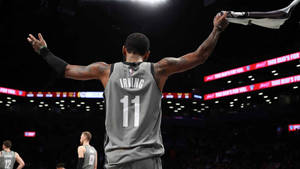 Kyrie Irving festeggia nell'arena di basket con le braccia alzate. — Brooklyn Sfondi