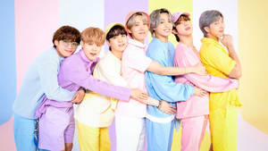 Seven smiling young men in pastel outfits linked arms against colorful stripes. — Bts Wallpaper