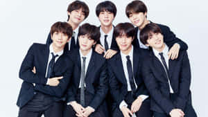 Seven K-pop idols in black suits posing together in a studio portrait. — Bts Wallpaper