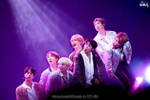 Seven K-pop idols performing on a purple lit stage in glittering jackets. — Bts Wallpaper