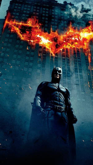 Batman si trova in una città oscura con un simbolo di pipistrello in fiamme sopra di lui. — Fuoco Sfondi