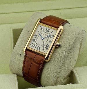 Gyldent Cartier Tank-ur med brun læderrem på udstillingspude. — Ur Wallpapers