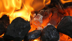 Braci incandescenti e fiamme in un braciere che proiettano una calda luce arancione. — Calore Sfondi
