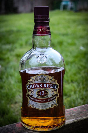 Chivas Regal whisky-flaske på treoverflate med gressbakgrunn — Whiskey Bakgrunner