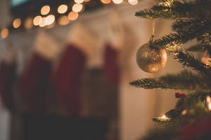 Nærbillede af et guldglitterpynt på et juletræ med slørede strømper og lys. — Gold Wallpapers