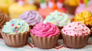 Fila di cupcake decorati con glassa colorata e codette. — Cupcake Sfondi