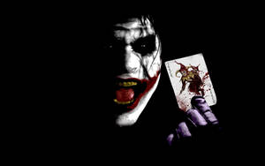 Joker tenant une carte joker ensanglantée avec un sourire sinistre. — Dark Fonds d'écran