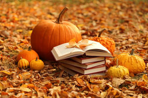 Stapel Bücher mit einem Blatt darauf, umgeben von Kürbissen und Herbstlaub. — Cool Wallpaper