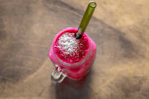 En rosa smoothie med kokosflak og grønt sugerør i et glasskrukke på tre. — Aesthetic Bakgrunner