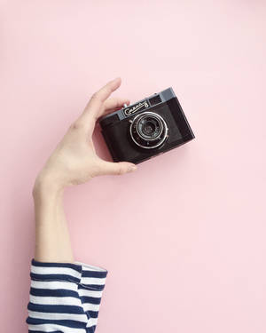 Hand houdt vintage camera tegen roze achtergrond — Camera Achtergronden