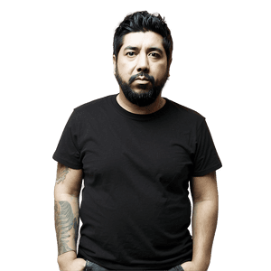 A bearded man with tattoos on his arm wearing a black t-shirt in a studio portrait. — Deftones Wallpaper