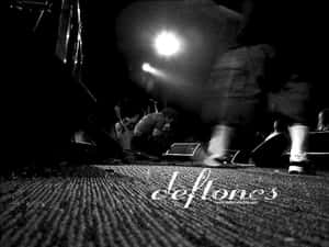Blurry musician playing guitar under bright stage light at a concert. — Deftones Wallpaper