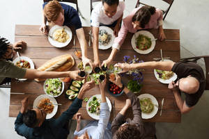 Amigos levantando copas en un brindis alrededor de una mesa de madera con comida. — Fiesta Fondos de pantalla