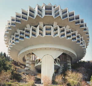 A large white tiered hotel building with balconies on a hillside under a blue sky. — Hotel Wallpaper