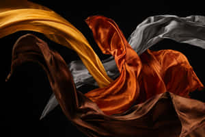 Luxurious flowing silk fabric in gold bronze and silver against black background — Dynamic Wallpaper