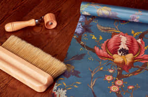 Wooden brush and roller next to floral wallpaper roll on wooden floor. — Applicable Wallpaper