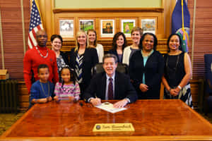 El gobernador Sam Brownback firma un documento con personal y niños en una oficina oficial. — Política Fondos de pantalla