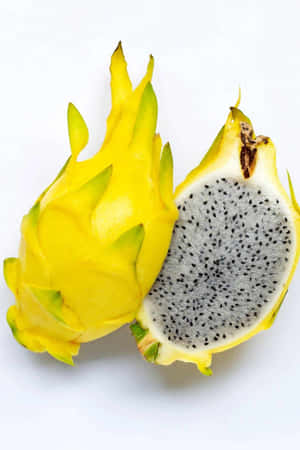 A whole and halved yellow dragon fruit with black seeds on a white background. — Fruit Wallpaper