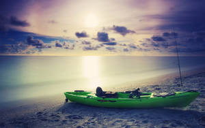 Un kayak vert sur une plage au coucher du soleil avec des eaux océaniques calmes et un soleil éclatant. — Kayak Fonds d'écran