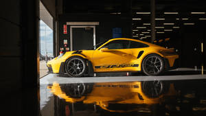 Yellow Porsche GT3 RS parked in garage with glossy floor reflection. — Yellow Wallpaper