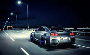 Auto sportiva argentata con cerchi blu che sfreccia su un ponte illuminato di notte. — Auto Sfondi