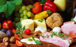 A colorful assortment of gourmet foods including cheese fruit meat and herbs on a wooden board. — Fruits Wallpaper