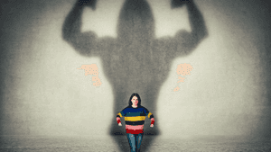 A woman stands before a wall where her shadow forms a giant muscular figure. — Hero Wallpaper