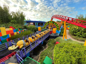 En fargerik berg-og-dalbane med bananvogner slynger seg gjennom en Lego-park. — Hollywood Bakgrunner