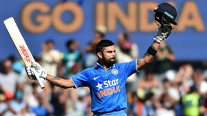 Cricketspelaren Virat Kohli firar seger med slagträ och hjälm lyfta. — Wave Bakgrundsbilder